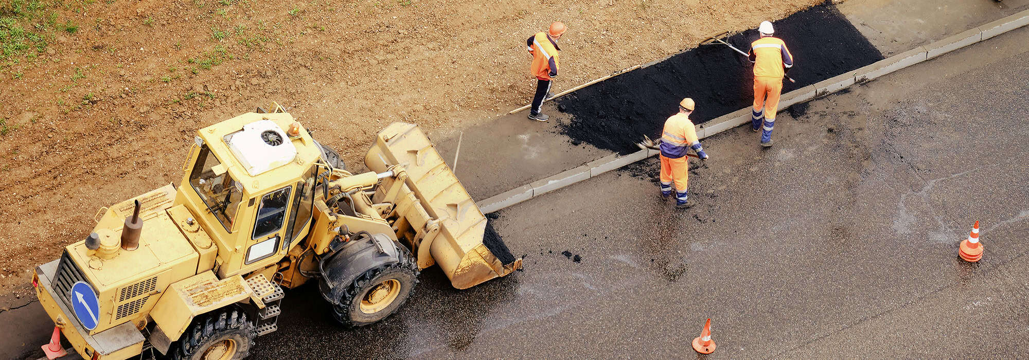 Excavator and construction workers laying asphalt